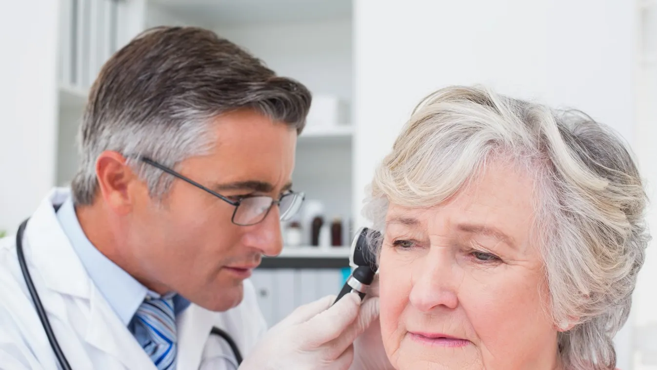 Doctor examining patients ear with otoscope