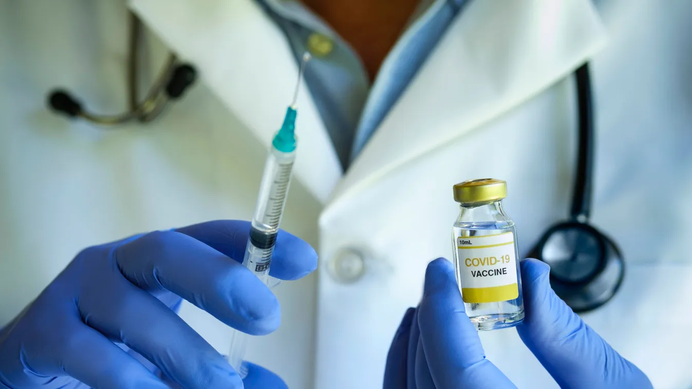 Close-up of doctors hands holding Covid1-19 vaccine and syringe
