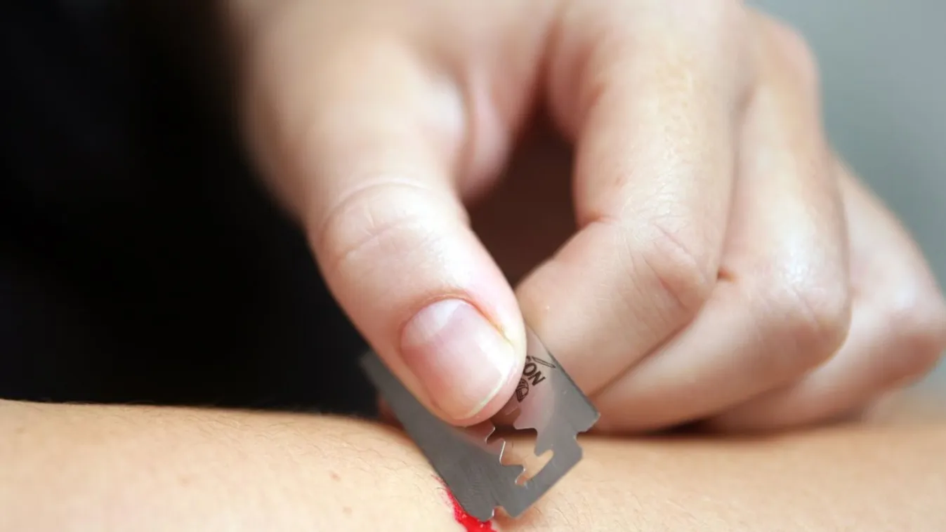 young woman hurts herself with a razor blade