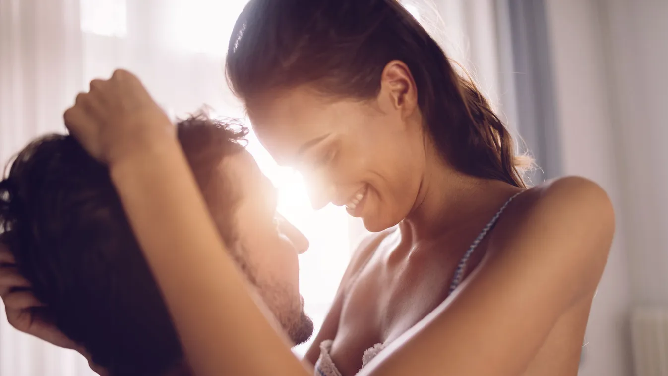 Passionate beautiful couple in bedroom enjoying foreplay