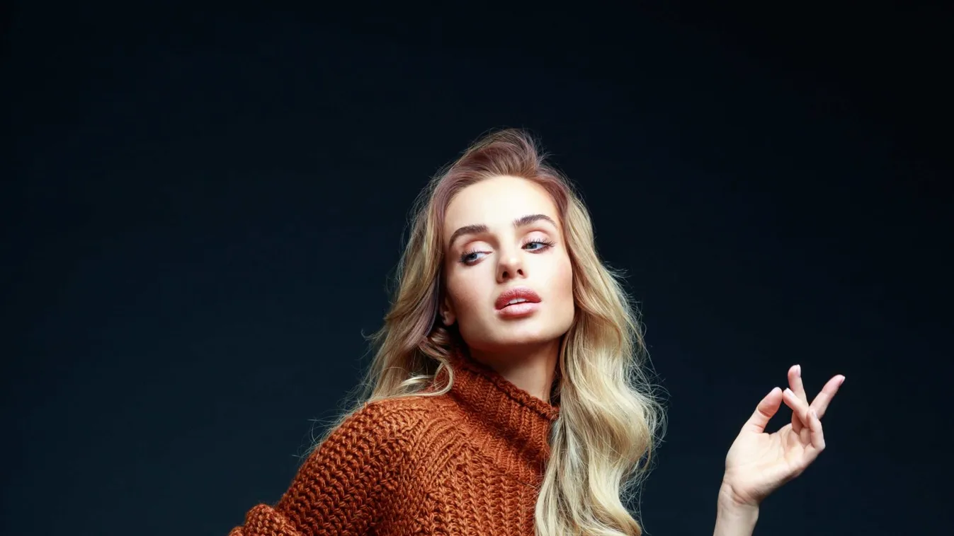 Fashion portrait of elegant woman in brown clothes, dark background
