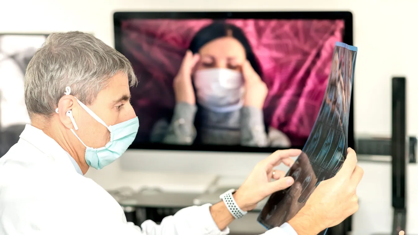 Doctor analyzing xray of patient with coronavirus with patient in videocall on the computer screen.