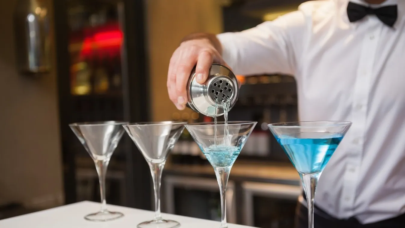 Bartender pouring blue alcohol into cocktail glass