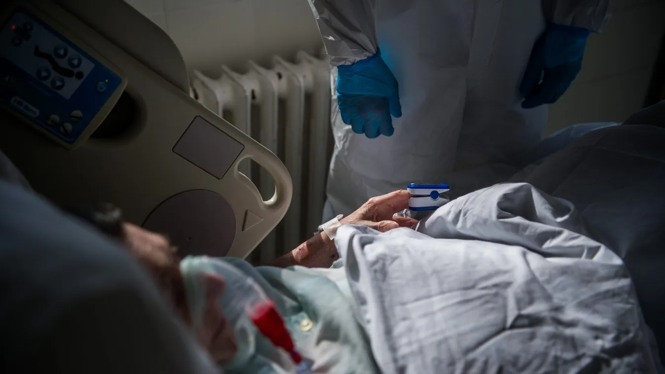 Védõfelszerelést viselõ orvos megméri egy beteg véroxigénszintjét a fõvárosi Honvédkórház koronavírussal fertõzött betegek fogadására kialakított osztályán