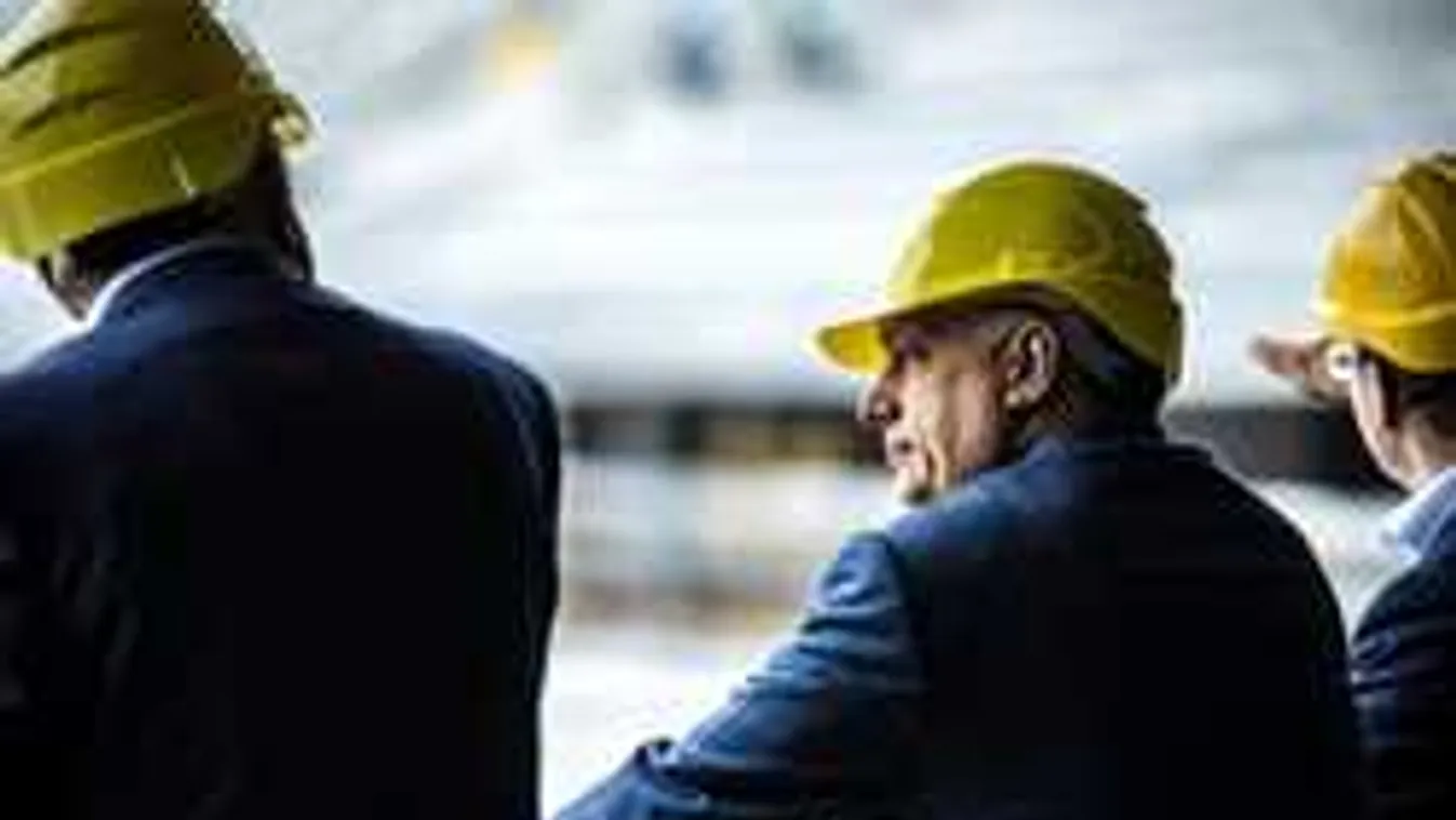 Orbán és Csányi sárga sisakban, pilonok között. Mi az?