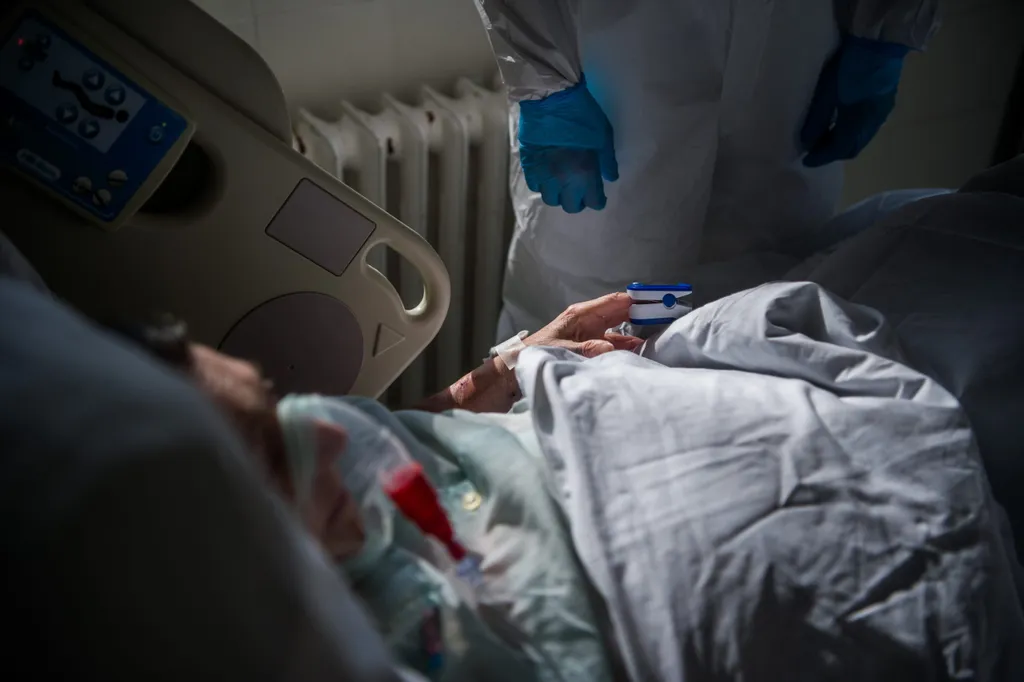 Védõfelszerelést viselõ orvos megméri egy beteg véroxigénszintjét a fõvárosi Honvédkórház koronavírussal fertõzött betegek fogadására kialakított osztályán