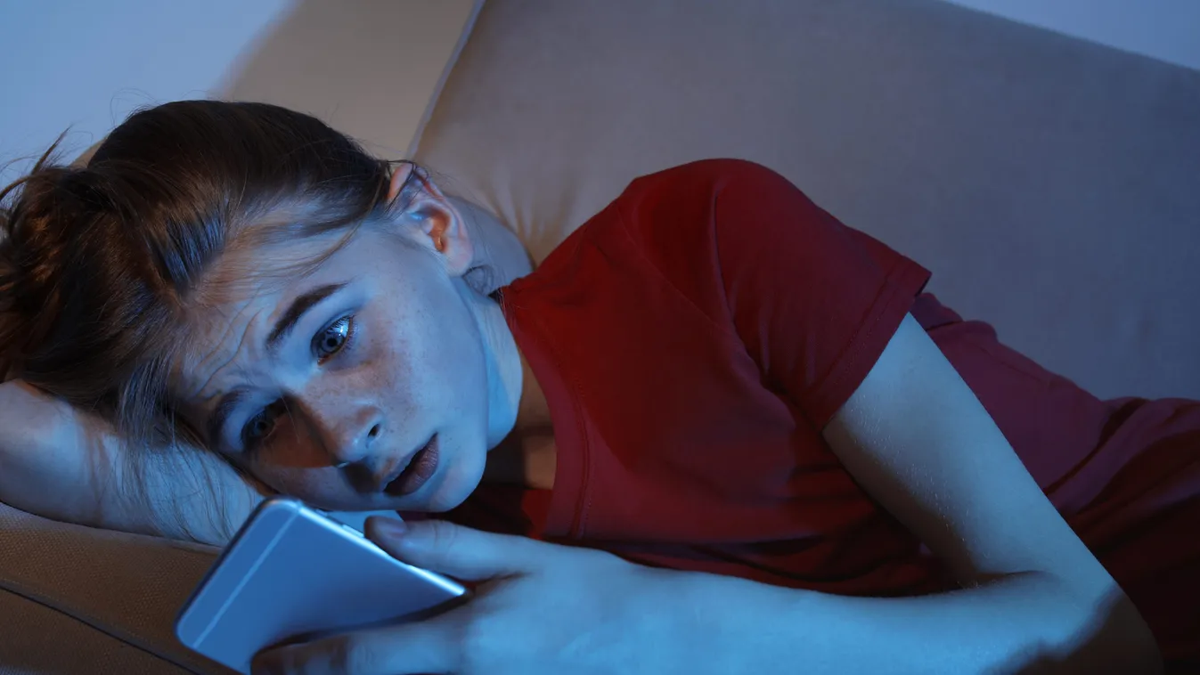 Shocked,Teenage,Girl,With,Smartphone,On,Sofa,In,Dark,Room.