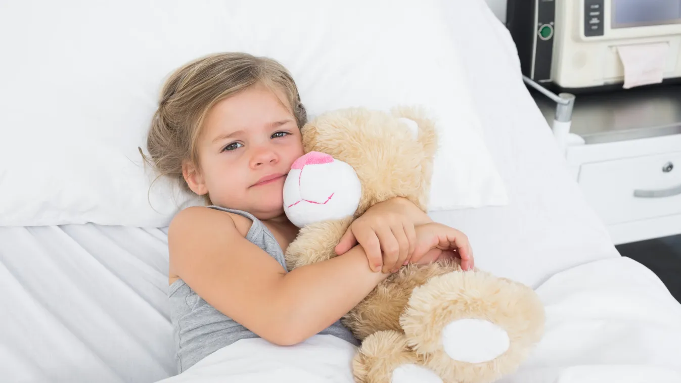 High angle portrait of cute girl embracing teddy bear while lying in hospital bed