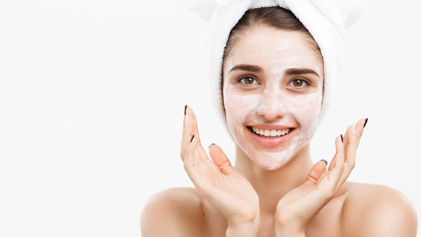 Beauty Skin Care Concept - Beautiful Caucasian Woman Face Portrait applying cream mask on her facial skin white background.