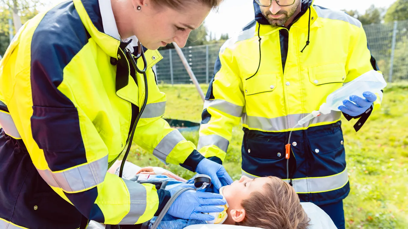 Paramedics measuring blood pressure of injured boy