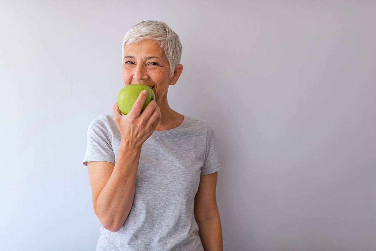 Portrait,Of,Happy,Mature,Woman,Holding,Granny,Smith,Apple,At