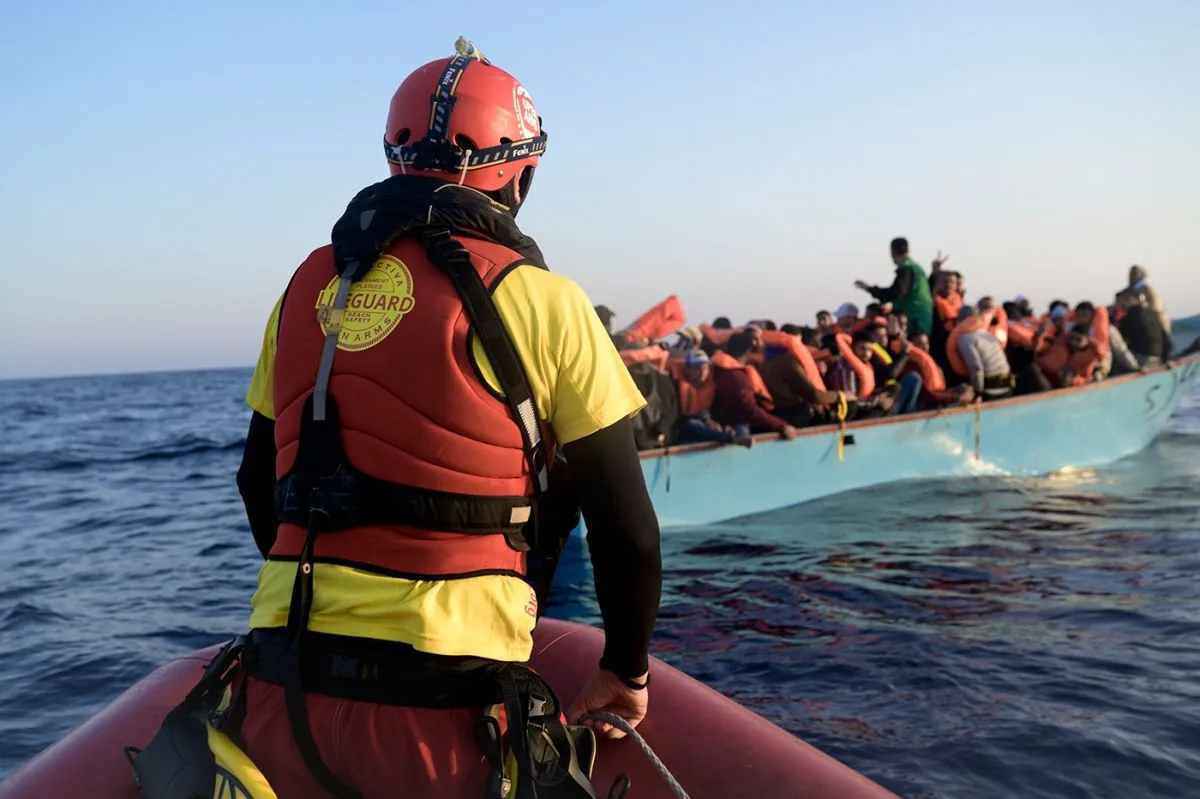 A rescuer seen in front of a group of migrants