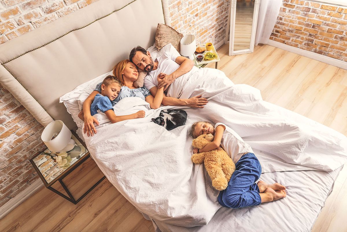 Family,Sleeping,Together,On,Bed