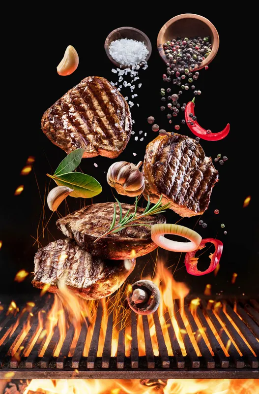 Grilled,Beef,Steaks,With,Vegetables,And,Spices,Fly,Over,The