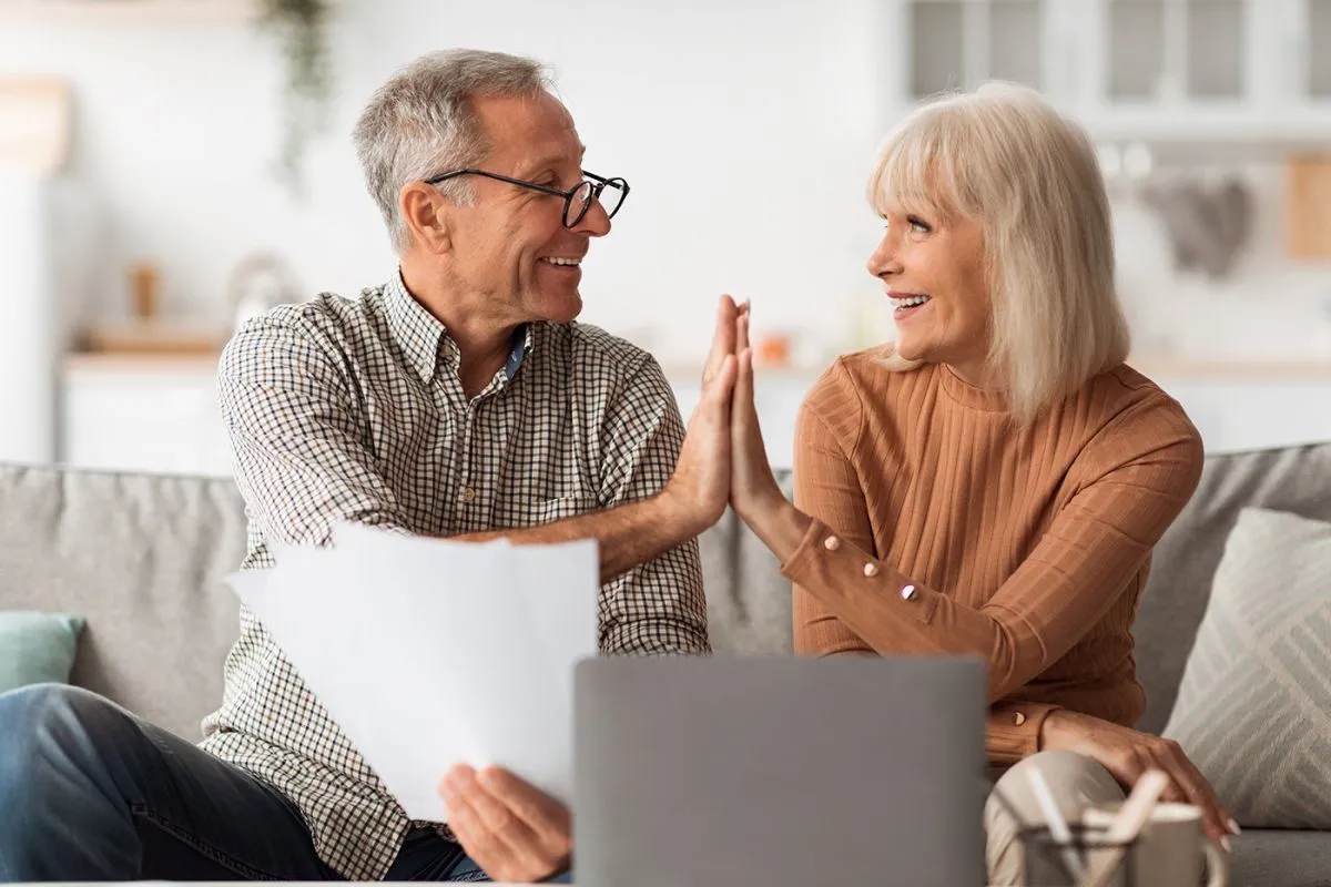 Happy,Senior,Couple,Giving,High-five,Holding,Papers,And,Documents,Sitting