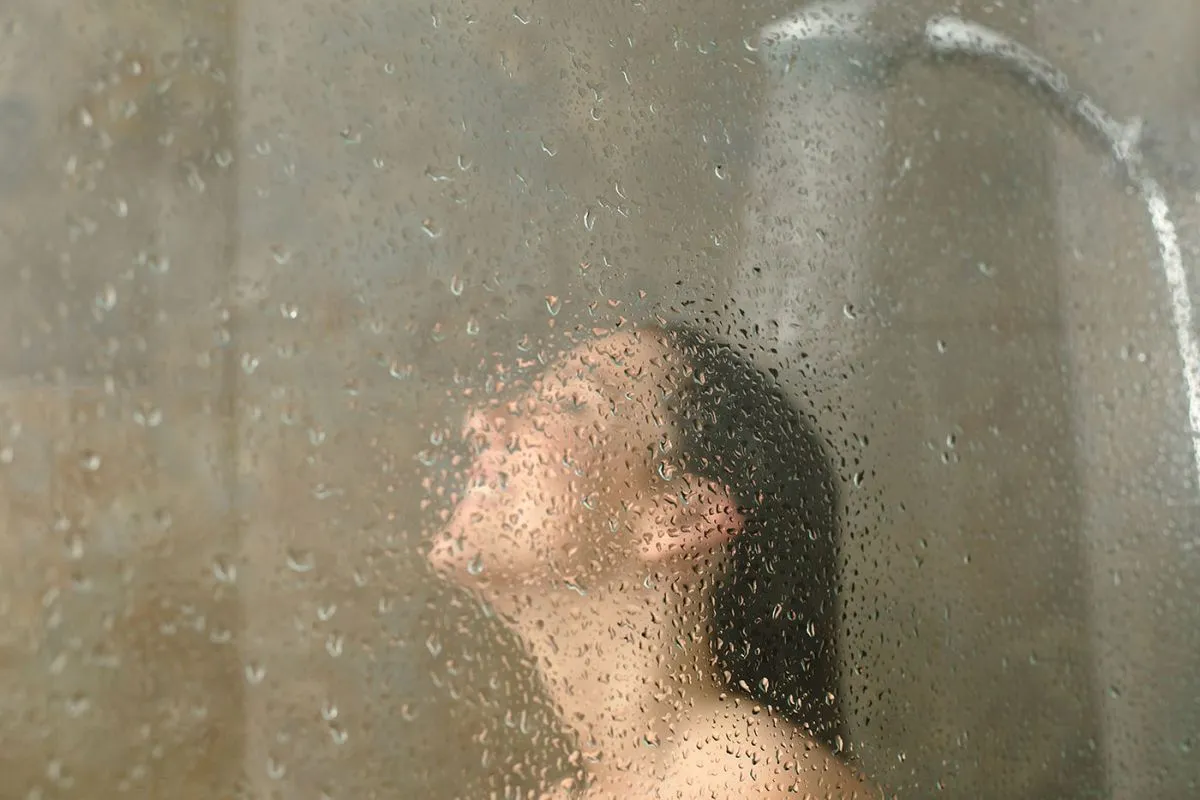 Woman,Having,Shower,Behind,Glass,With,Water,Drops,Standing,On