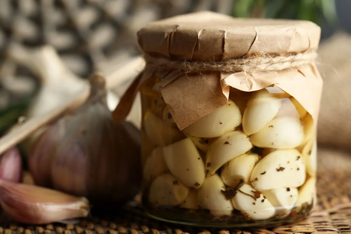 Canned,Garlic,In,Glass,Jar,And,Wicker,Mat,And,Rosemary