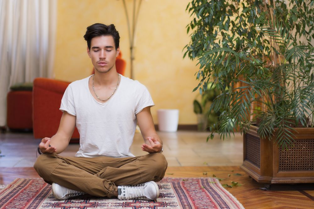 Young,Man,Meditating,On,His,Living,Room,Floor,Sitting,In
