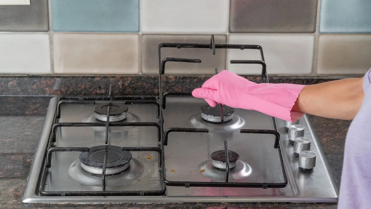 A,Woman's,Hand,Holds,The,Grate,From,The,Gas,Stove