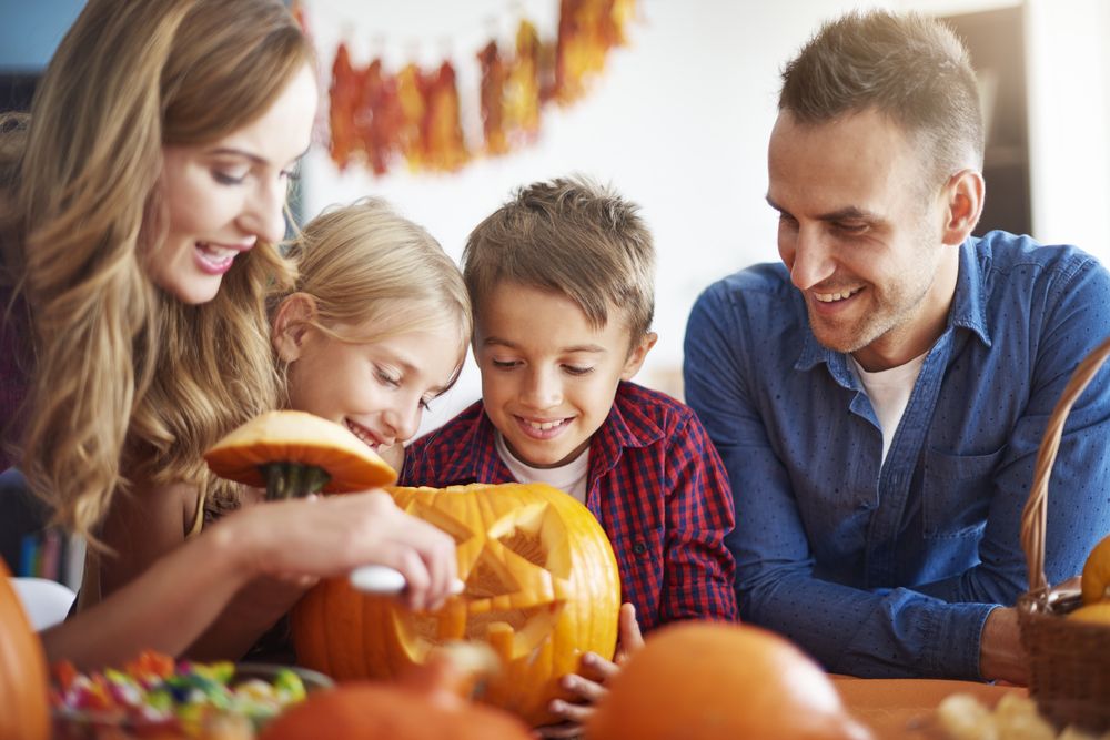 Parents,Helping,Children,In,Carving,Pumpkins