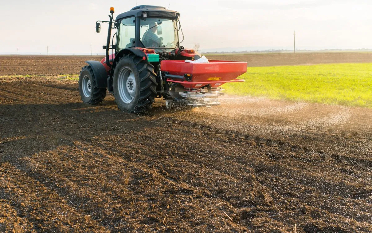 Tractor spreading artificial fertilizers  in field
