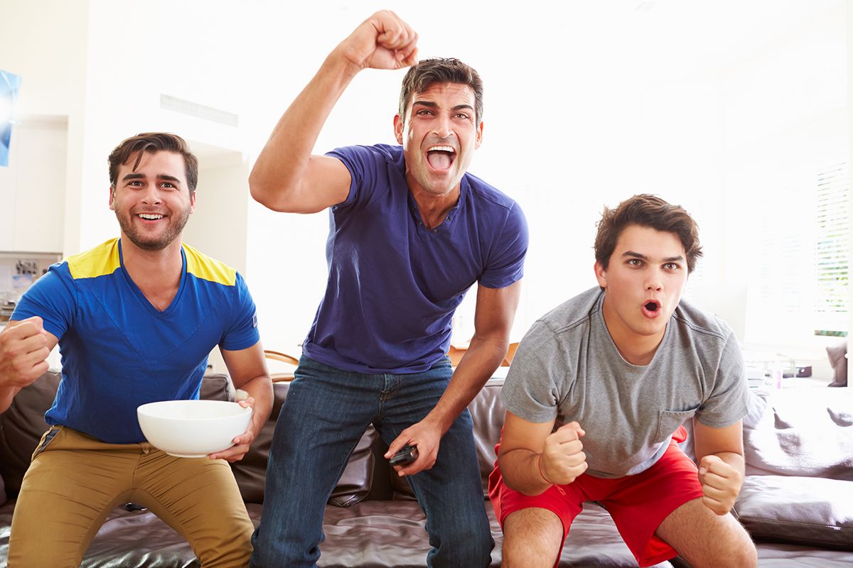 Group,Of,Men,Sitting,On,Sofa,Watching,Sport,Together