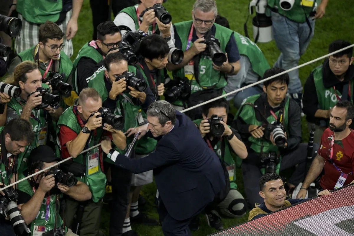 Cristiano Ronaldo (alul) mosolyog, mögötte a miatta a kispadot körüldongó fotósok hada