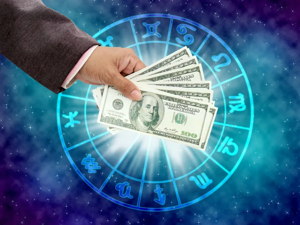 Hand,Holding,Money,On,The,Horoscope,Concept.