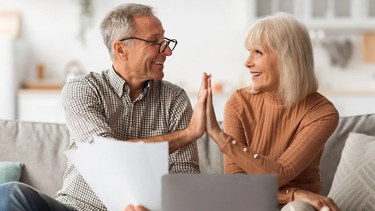 Happy,Senior,Couple,Giving,High-five,Holding,Papers,And,Documents,Sitting
