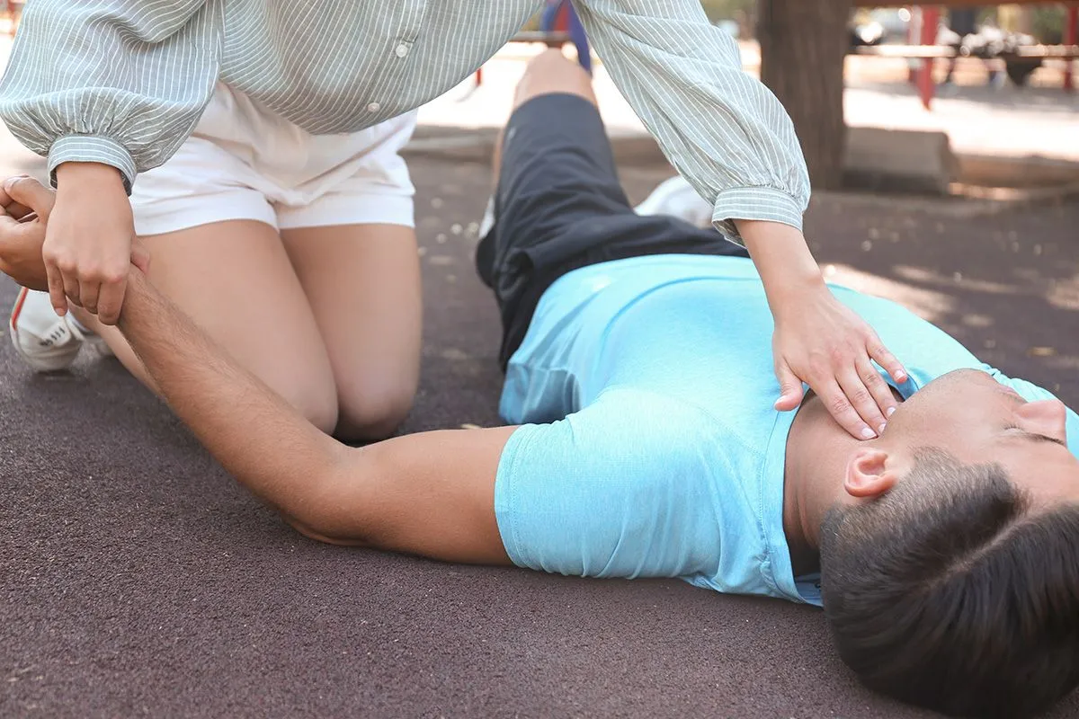 Young,Woman,Checking,Pulse,Of,Unconscious,Man,Outdoors.,First,Aid