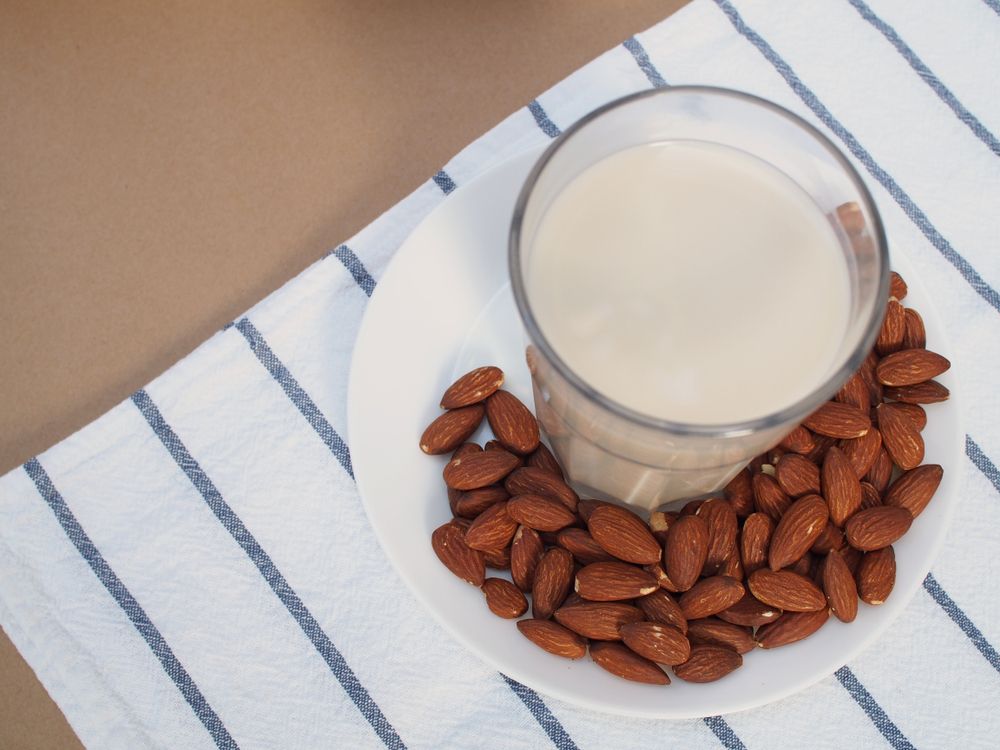 Almondmilk,And,Almond,On,White,Plate,And,Light,Brown,Background
