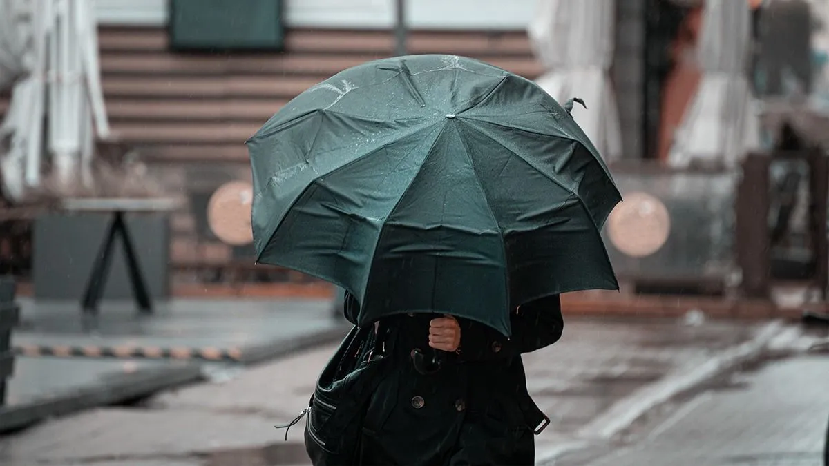 Woman,Walking,In,The,City,With,Green,Umbrella,On,Rainy