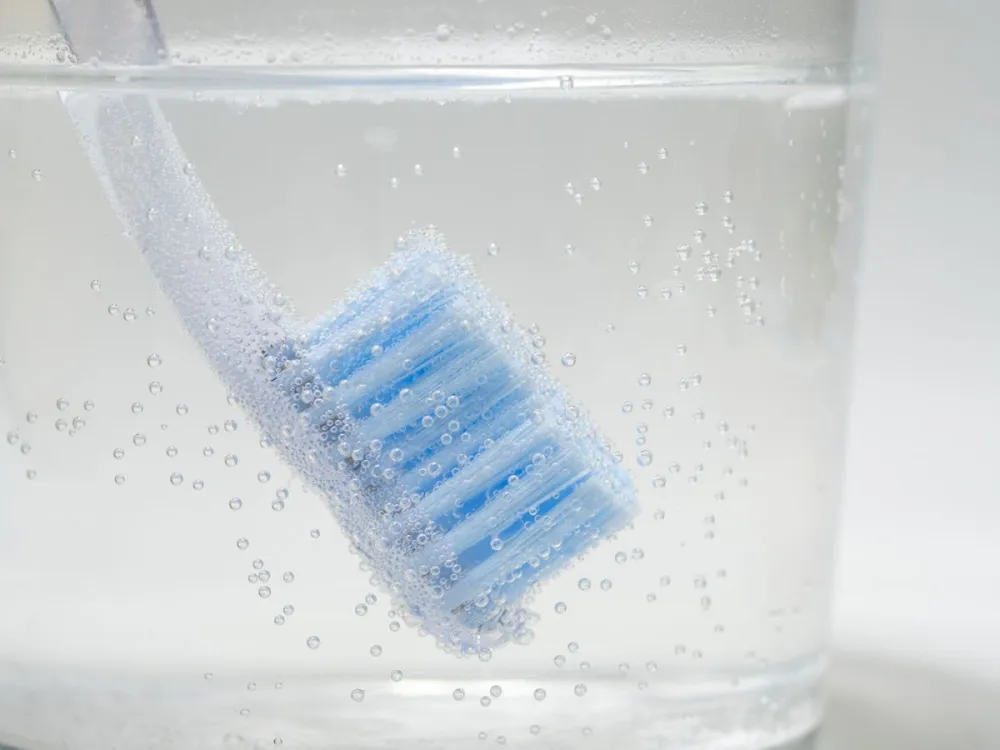 Disinfecting,A,Toothbrush,In,A,Glass,Of,Bubbly,Water.,Dental