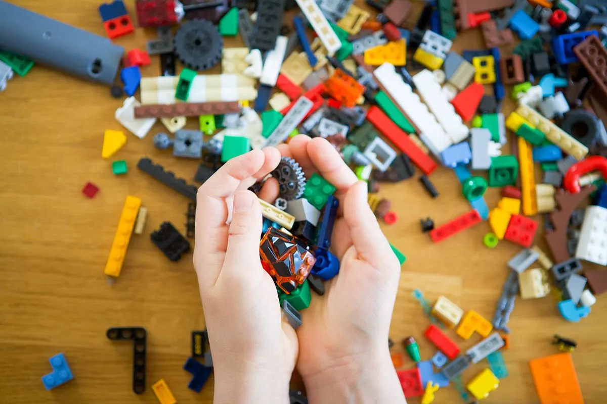 Close,Up,Of,Child's,Hands,Playing,With,Colorful,Plastic,Bricks