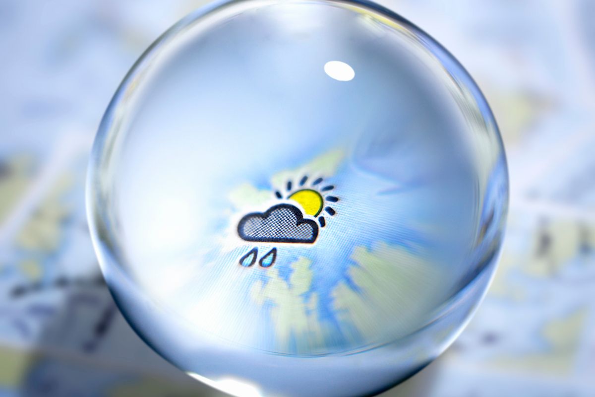 Close up of glass ball with rain cloud and sun in center