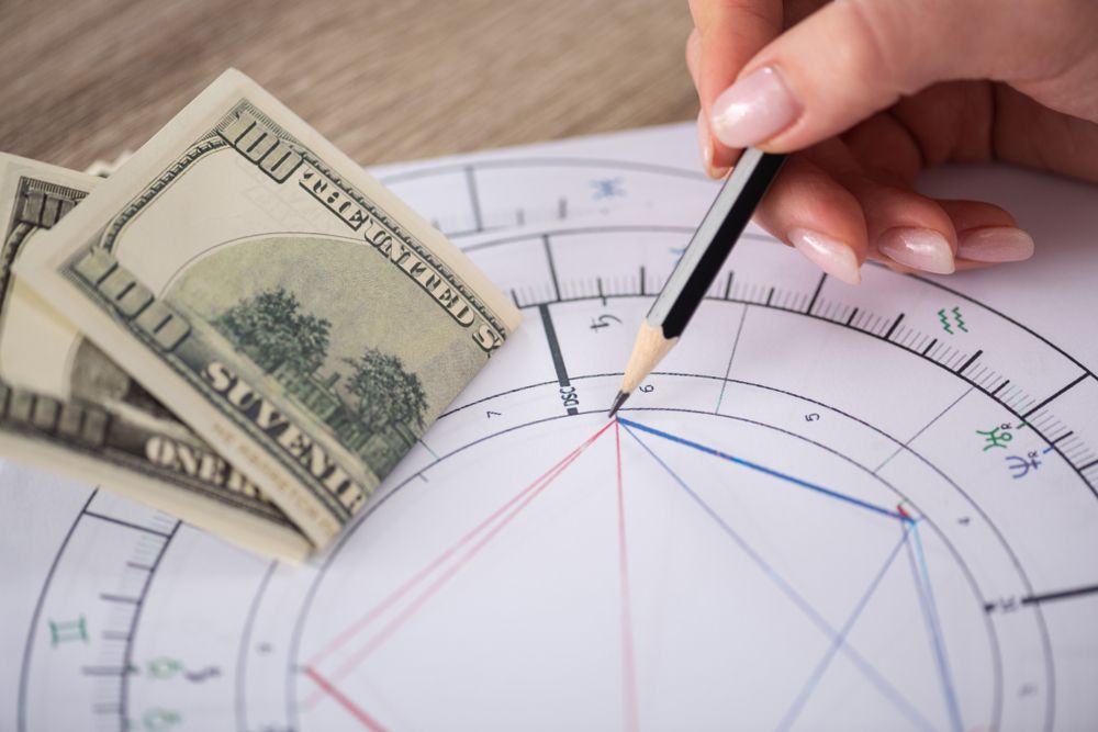 Cropped,View,Of,Astrologer,Drawing,Natal,Chart,Beside,Dollar,Banknotes