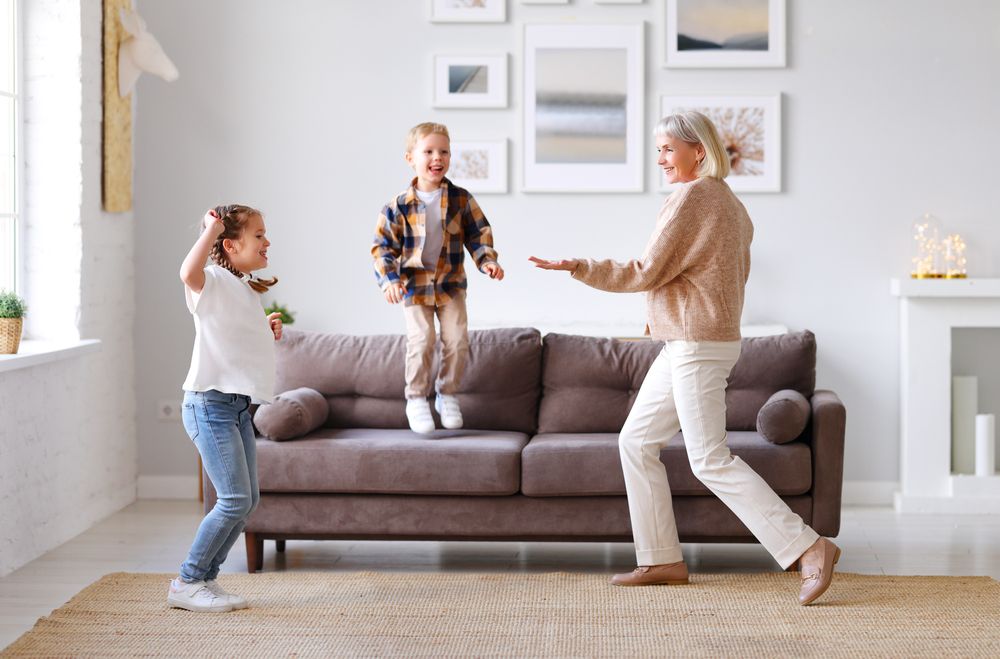 Delighted,Mature,Woman,Dancing,With,Cute,Kids,In,Living,Room