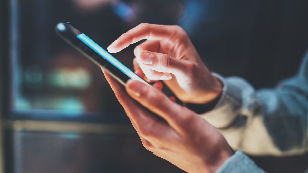 Closeup view of woman holding modern smartphone in hands.Girl typing on empty mobile screen. Horizontal, blurred background, bokeh effects.