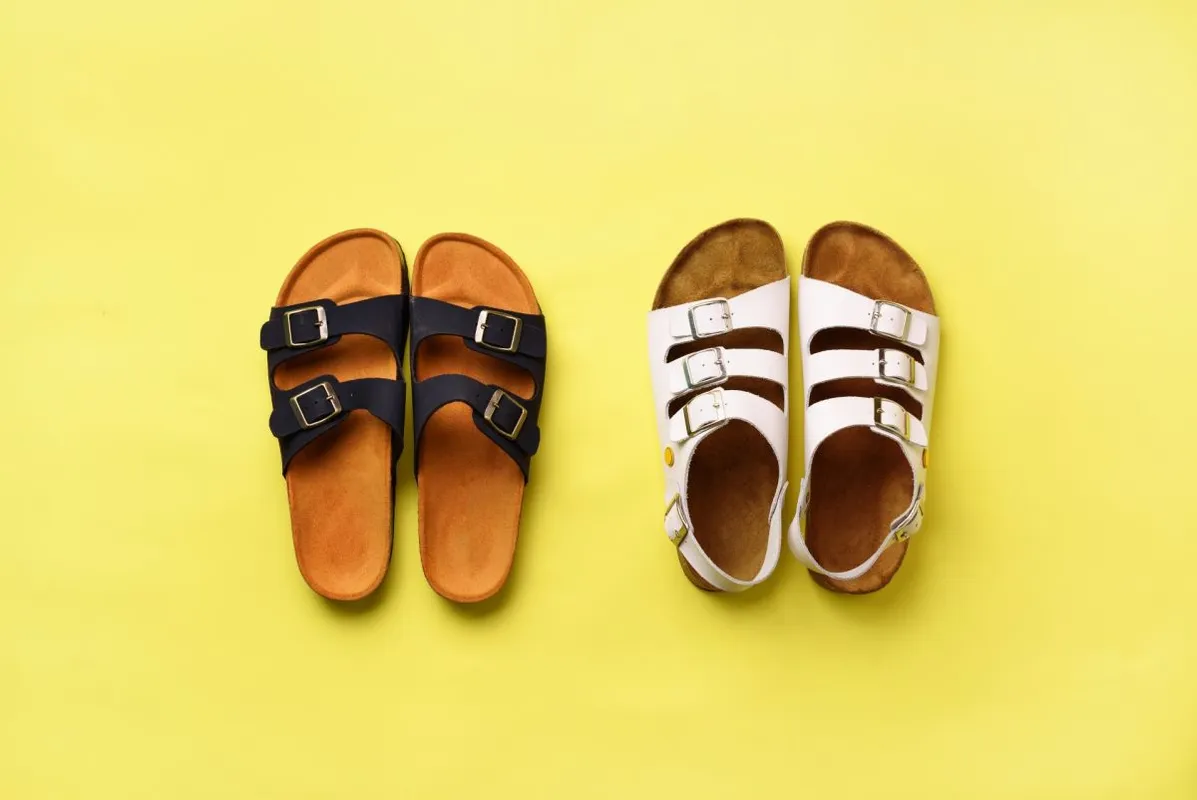 Summer female shoes - sandals (birkenstock) and slippers on yellow background with copy space. Top view. Minimal flat lay. Selection concept