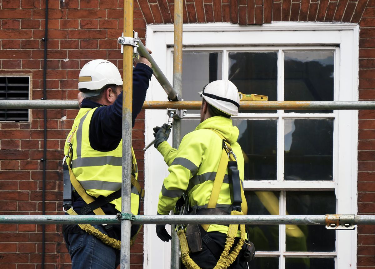 Two,Workers,Assembling,Scaffolding,On,City,Building