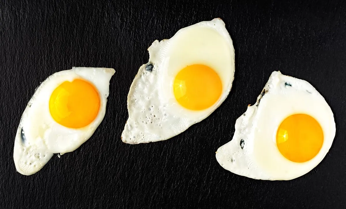 Three,Fried,Eggs,On,A,Black,Stone,Pan,,Flat,Lay.