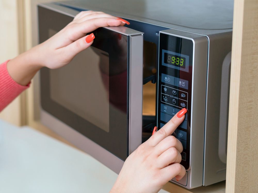 Detail,Of,Female,Hand,While,Using,The,Microwave