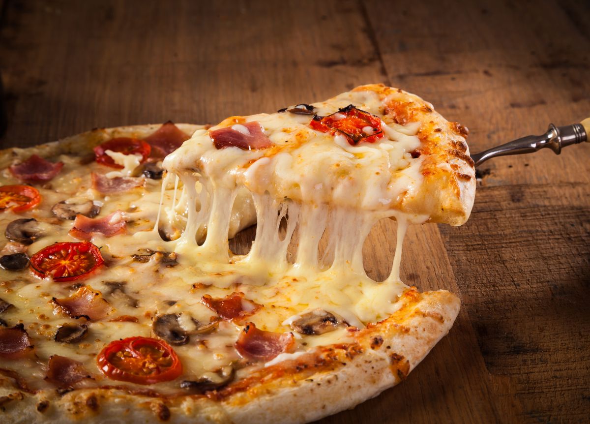 Hot,Pizza,Slice,With,Melting,Cheese,On,A,Rustic,Wooden