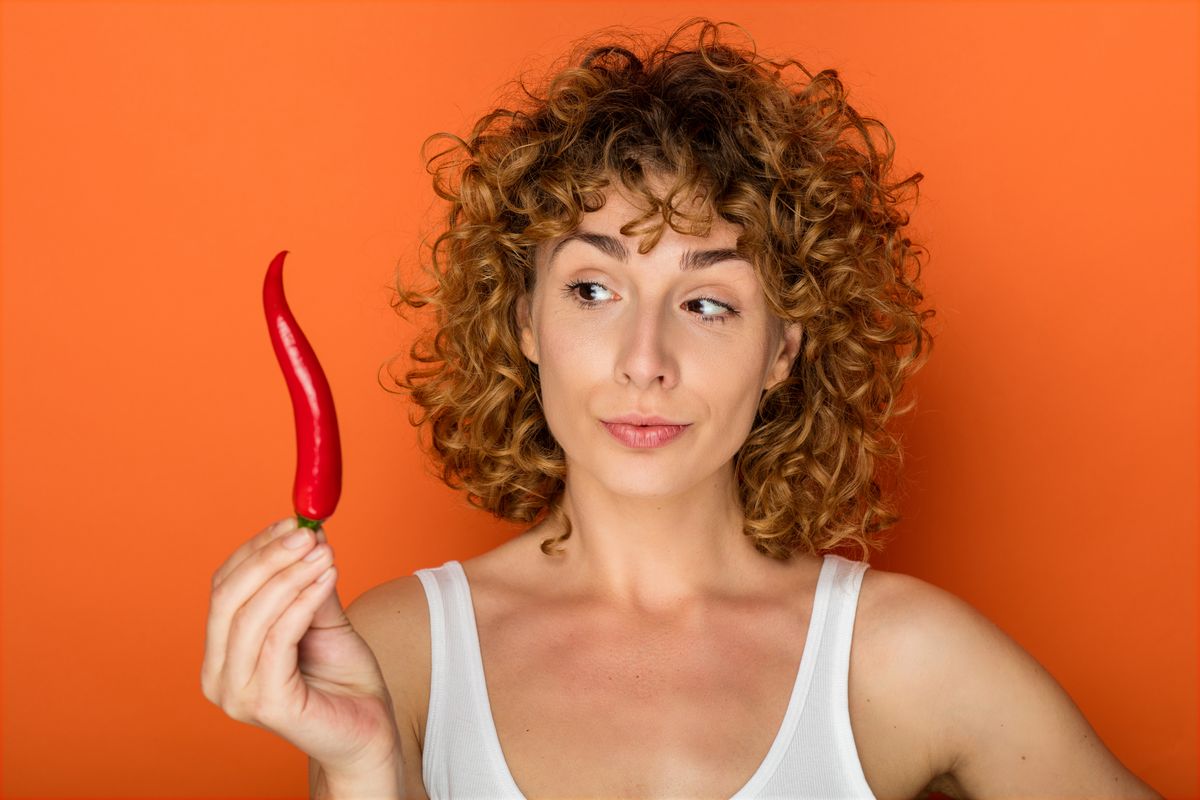 Young,Curly,Woman,On,Orange,Background,With,Chili,Pepper
