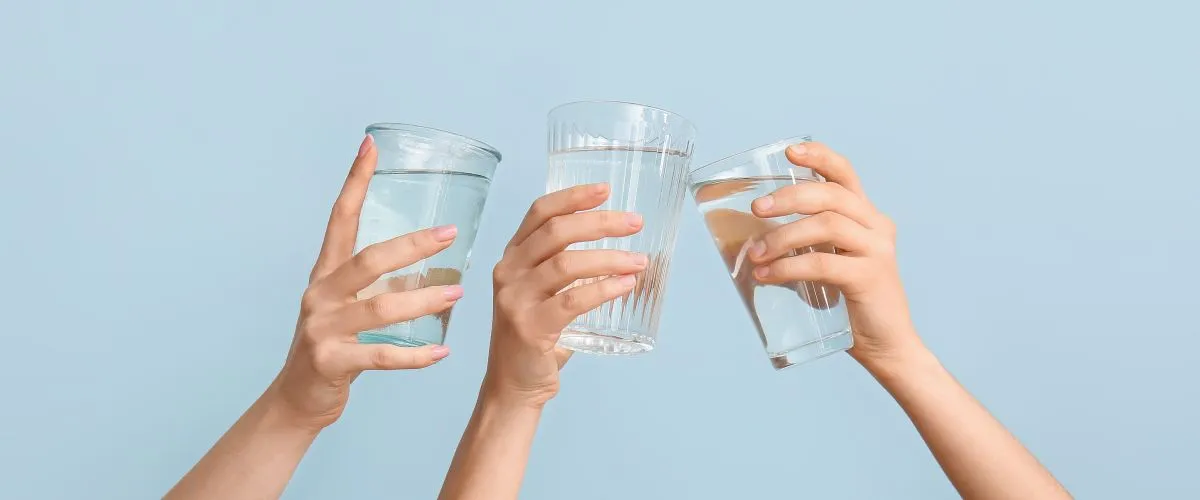 Female,Hands,With,Glasses,Of,Water,On,Light,Blue,Background,víz