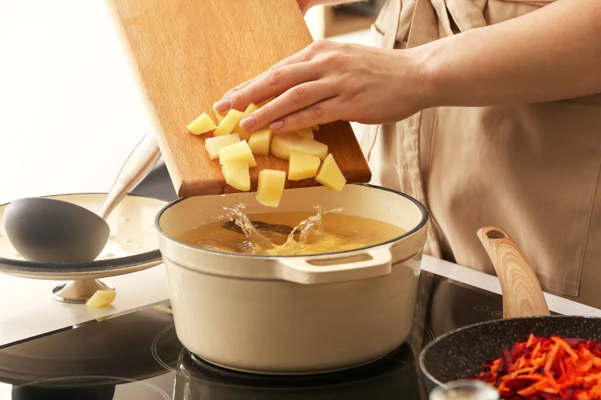 Woman,Adding,Potato,To,Cooking,Pot,In,Kitchen