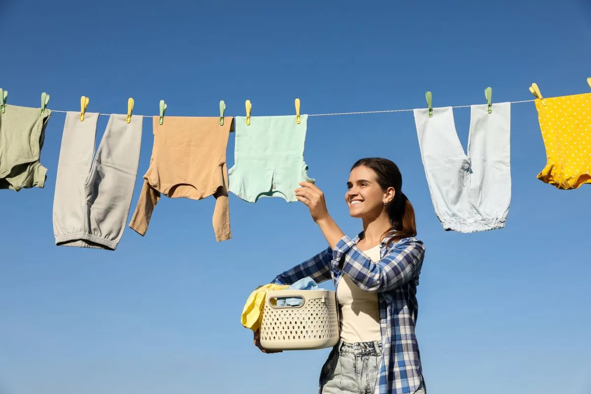 Smiling,Woman,Holding,Basket,With,Baby,Clothes,Near,Washing,Line