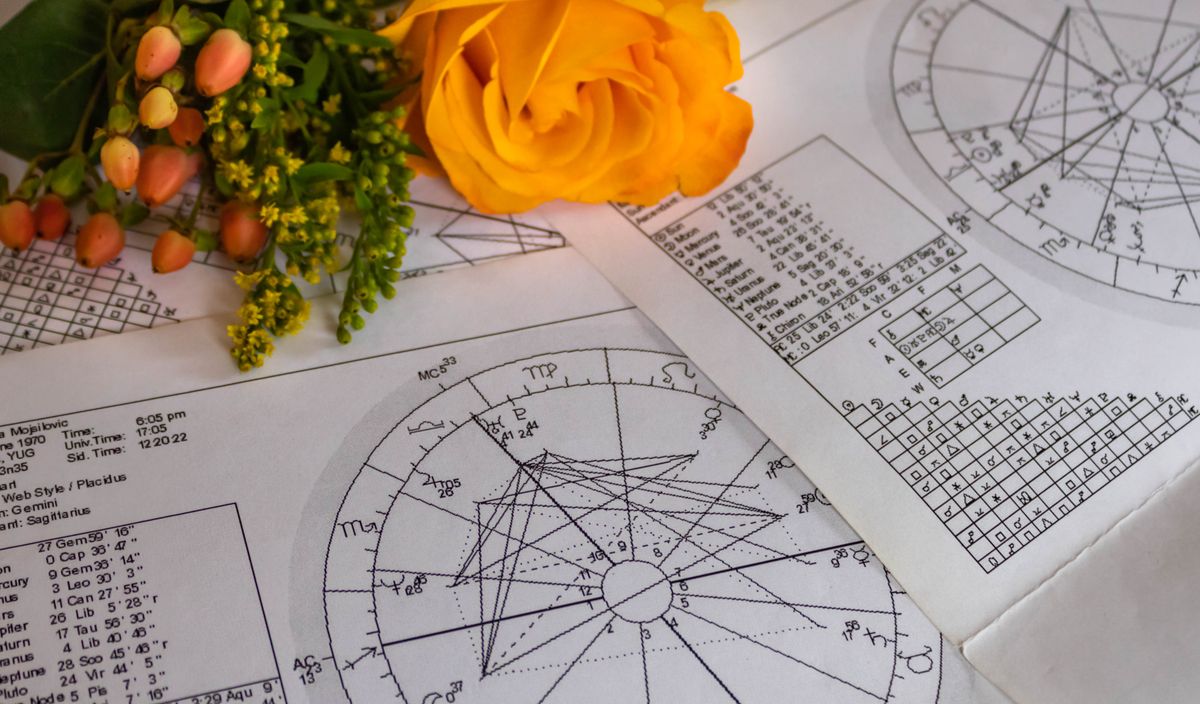 Printed,Astrology,Charts,With,Orange,Flowers,In,The,Background