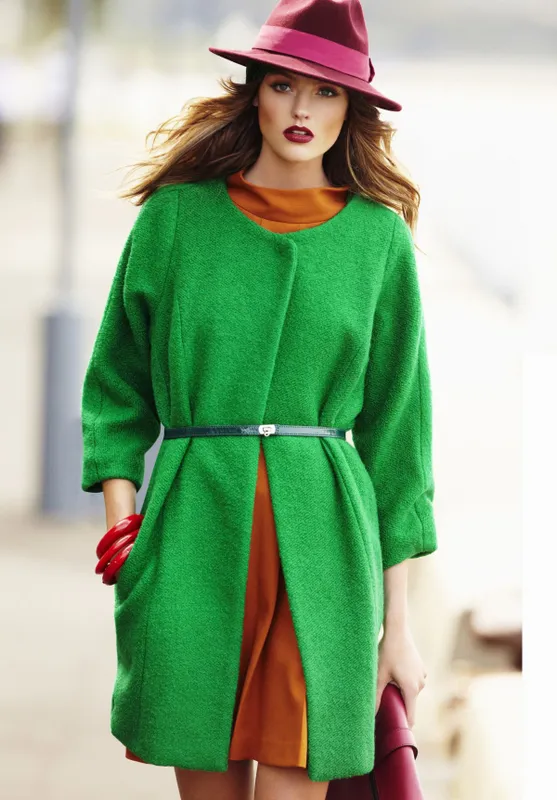 A young woman wearing a hat and a green coat