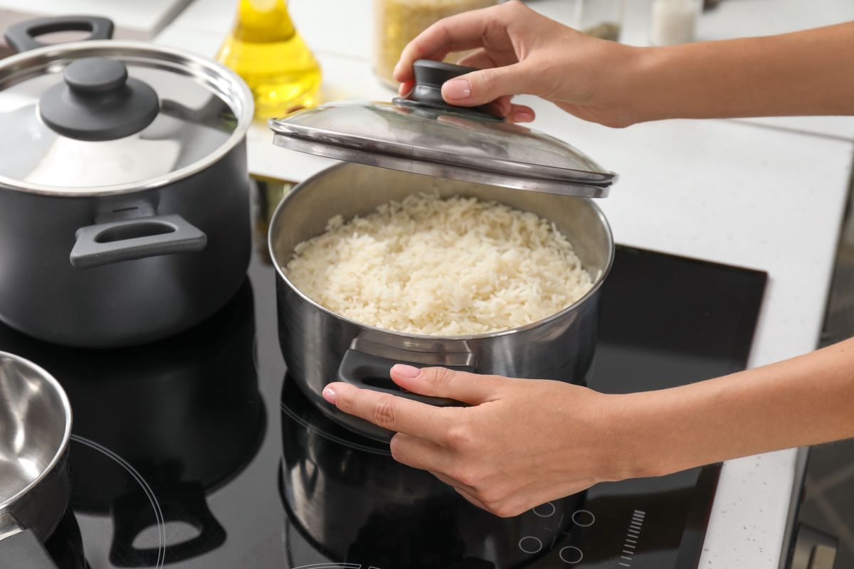 Woman,Cooking,Rice,On,Stove,In,Kitchen